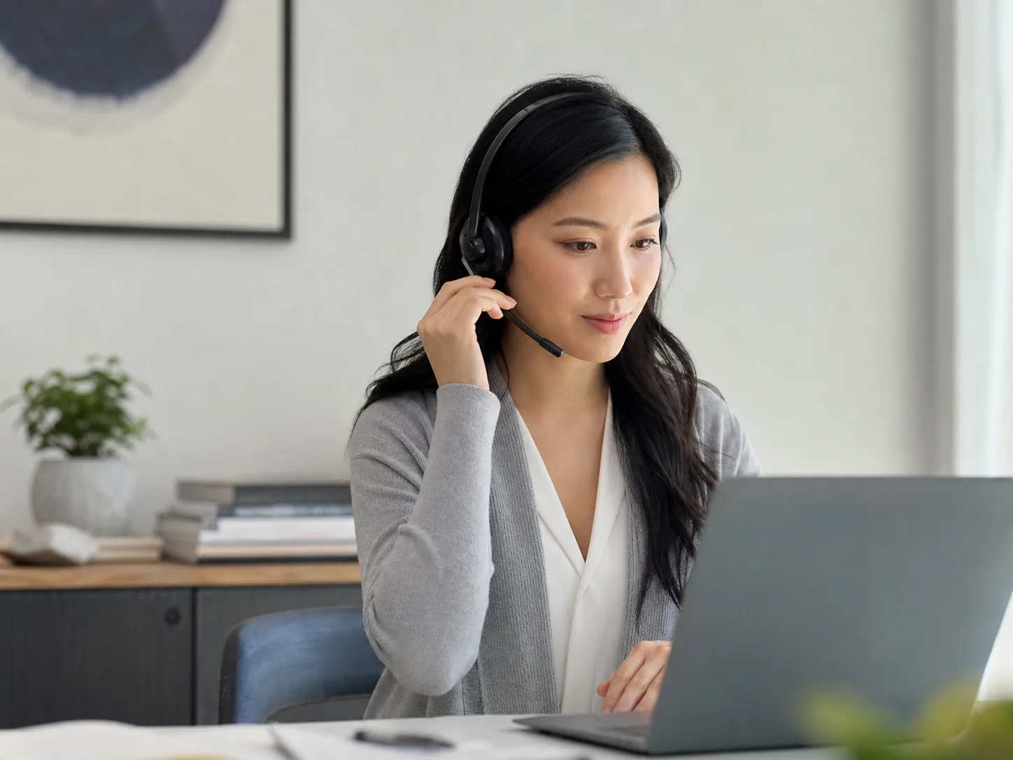 A woman wearing a headset while working at a laptop
